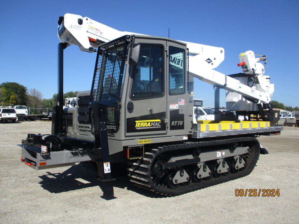 Custom tracked unit featuring a Terramac RT7U carrier, Versalift VST47 aerial lift, Alum-line flatbed, and Braden Winch, built for heavy-duty utility operations in tough terrains.